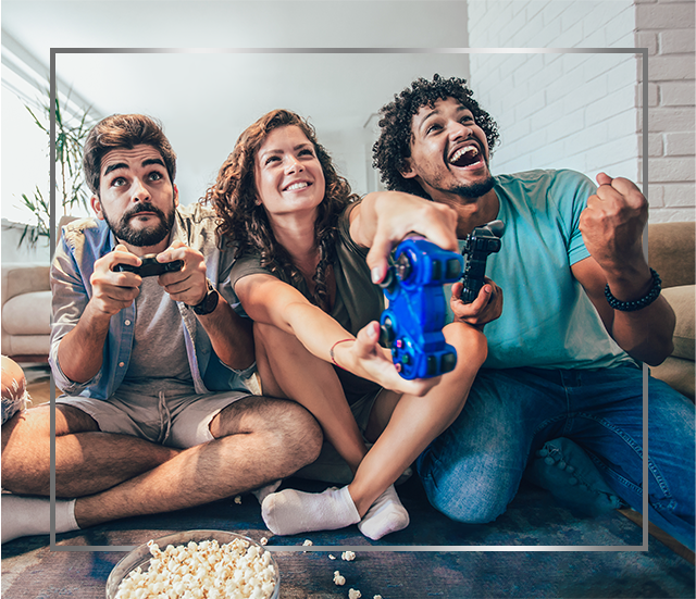 Group of young smiling people sitting on floor and playing video games, happy after Canesten athlete’s foot treatment