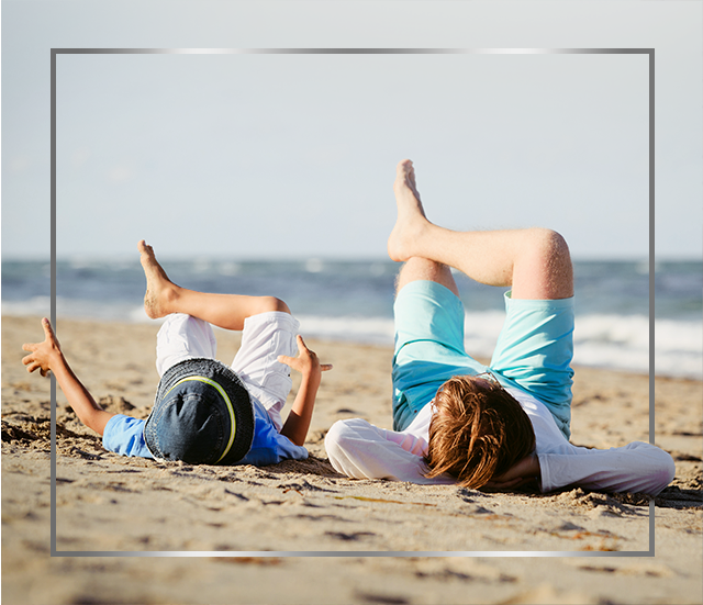 Mother and child lying on beach with crossed legs, happy after Canesten athlete’s foot treatment