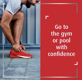 Smiling man in shorts tying red shoe, with the caption go to the gym or pool with confidence